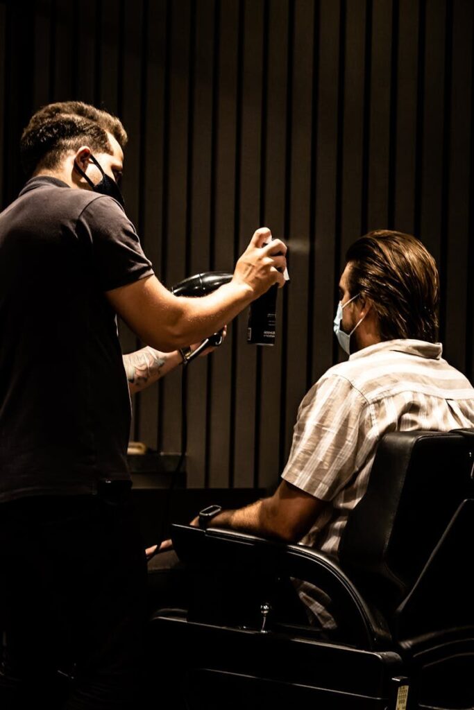 A barber wearing a mask styles a client's hair in a João Pessoa barbershop.