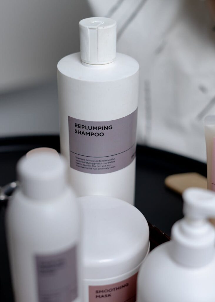 White bottles of replumping shampoo displayed on a black tray, ideal for haircare and cosmetics.